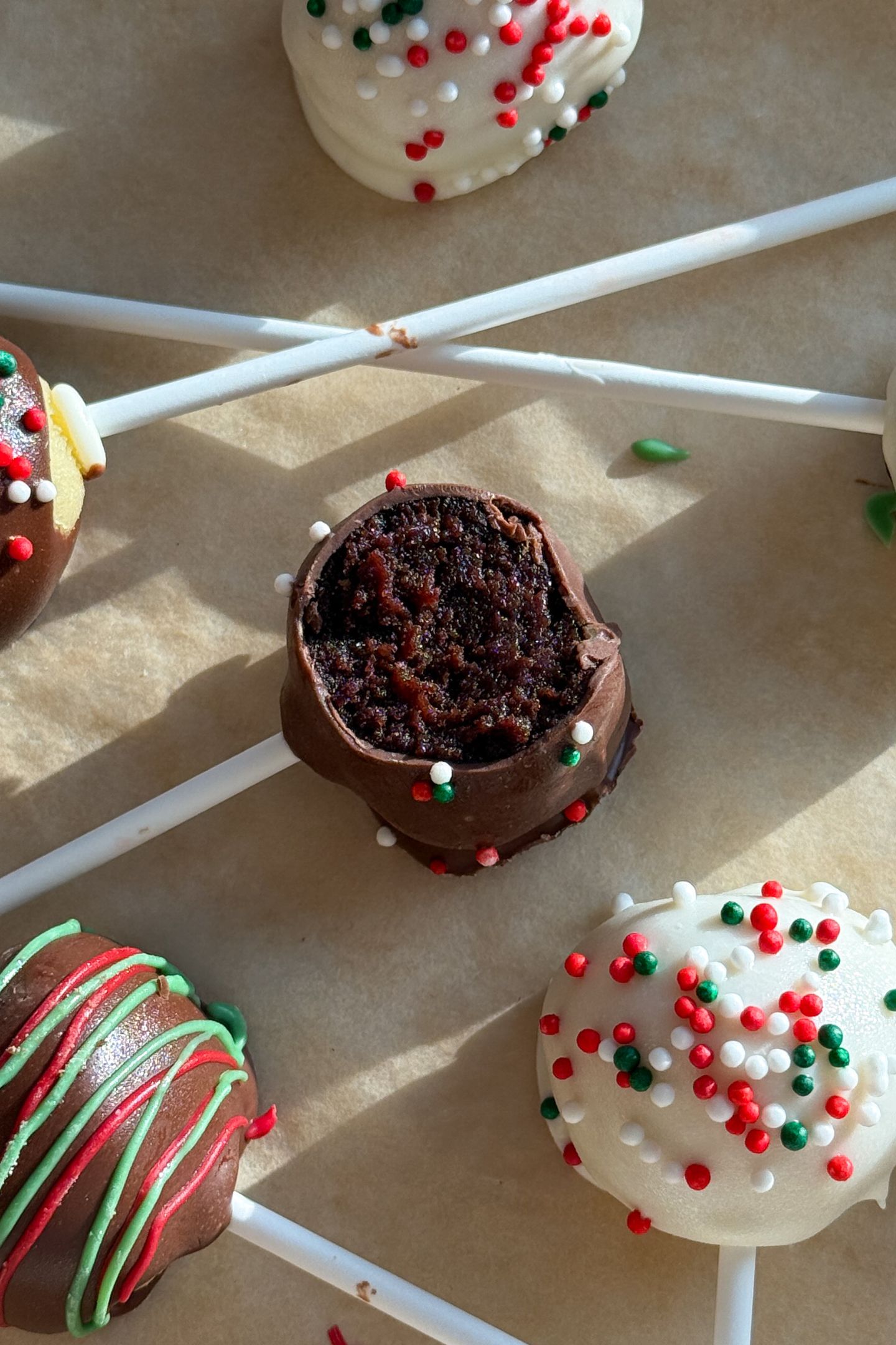 Chocolate Cake Pop with a bite taken out of it with Christmas decorations on them.