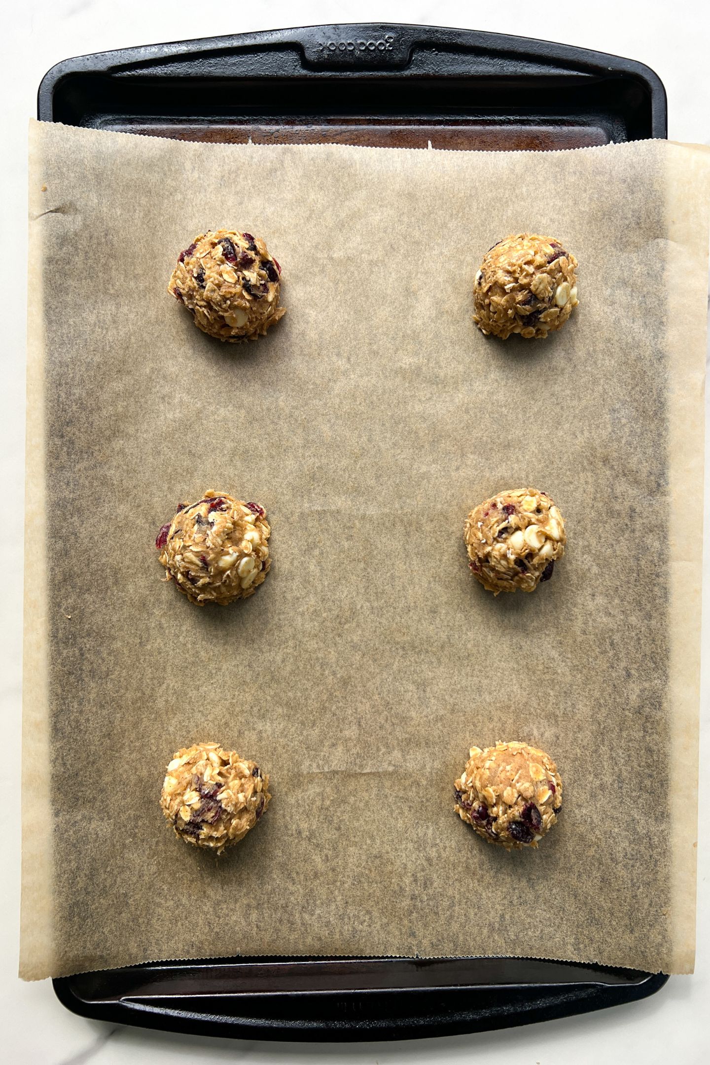 Portioned cookie dough on a baking sheet lined with parchment paper.