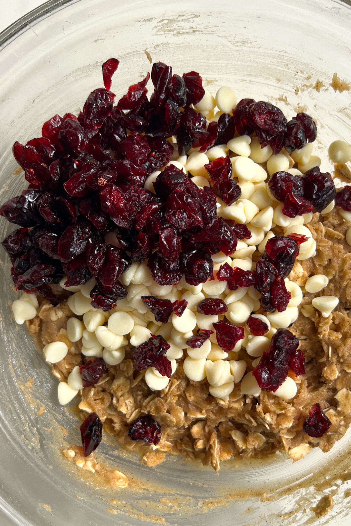 Adding cranberries and white chocolate chips to the bowl.