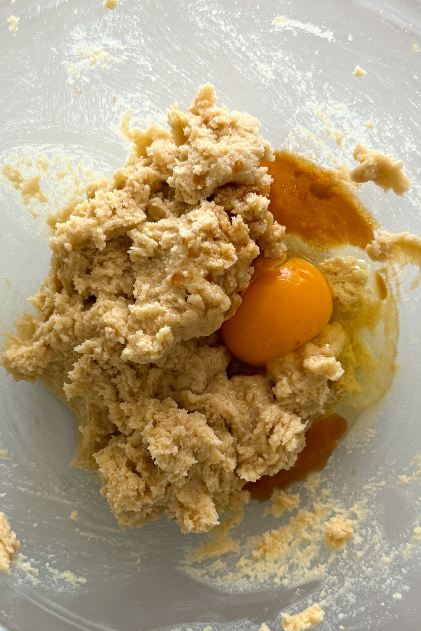 Butter and sugar combined in a mixing bowl topped with an egg and vanilla extract.