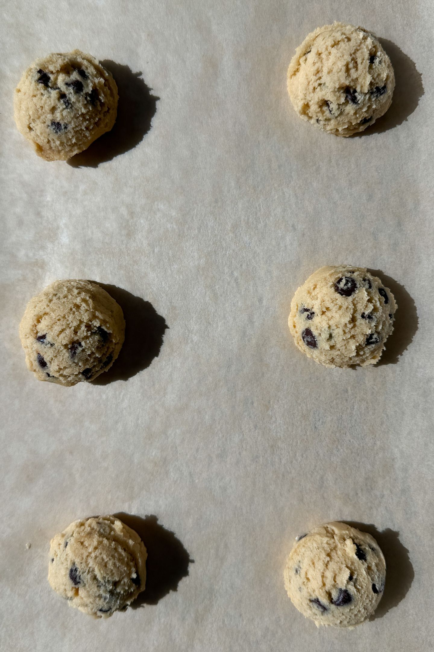 Portioned cookie dough on a baking sheet lined with parchment paper.