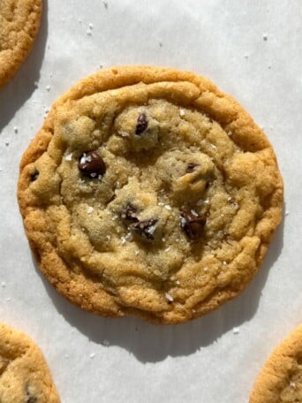 Thin and chewy chocolate chip cookies on parchment paper.