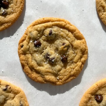 Thin and chewy chocolate chip cookies on parchment paper.