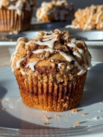 Cinnamon Streusel Muffin on a plate and topped with a vanilla glaze drizzle.