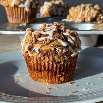 Cinnamon Streusel Muffin on a plate and topped with a vanilla glaze drizzle.