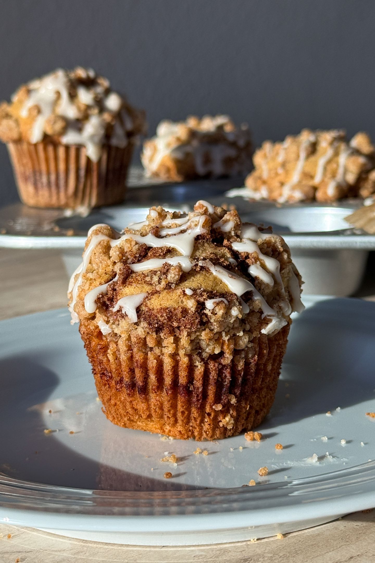 Cinnamon Streusel Muffin on a plate and topped with a vanilla glaze drizzle.