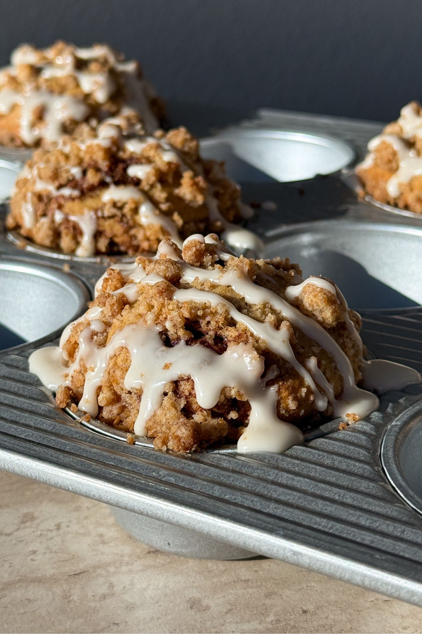 Baked muffins in the muffin tin topped with a vanilla glaze.