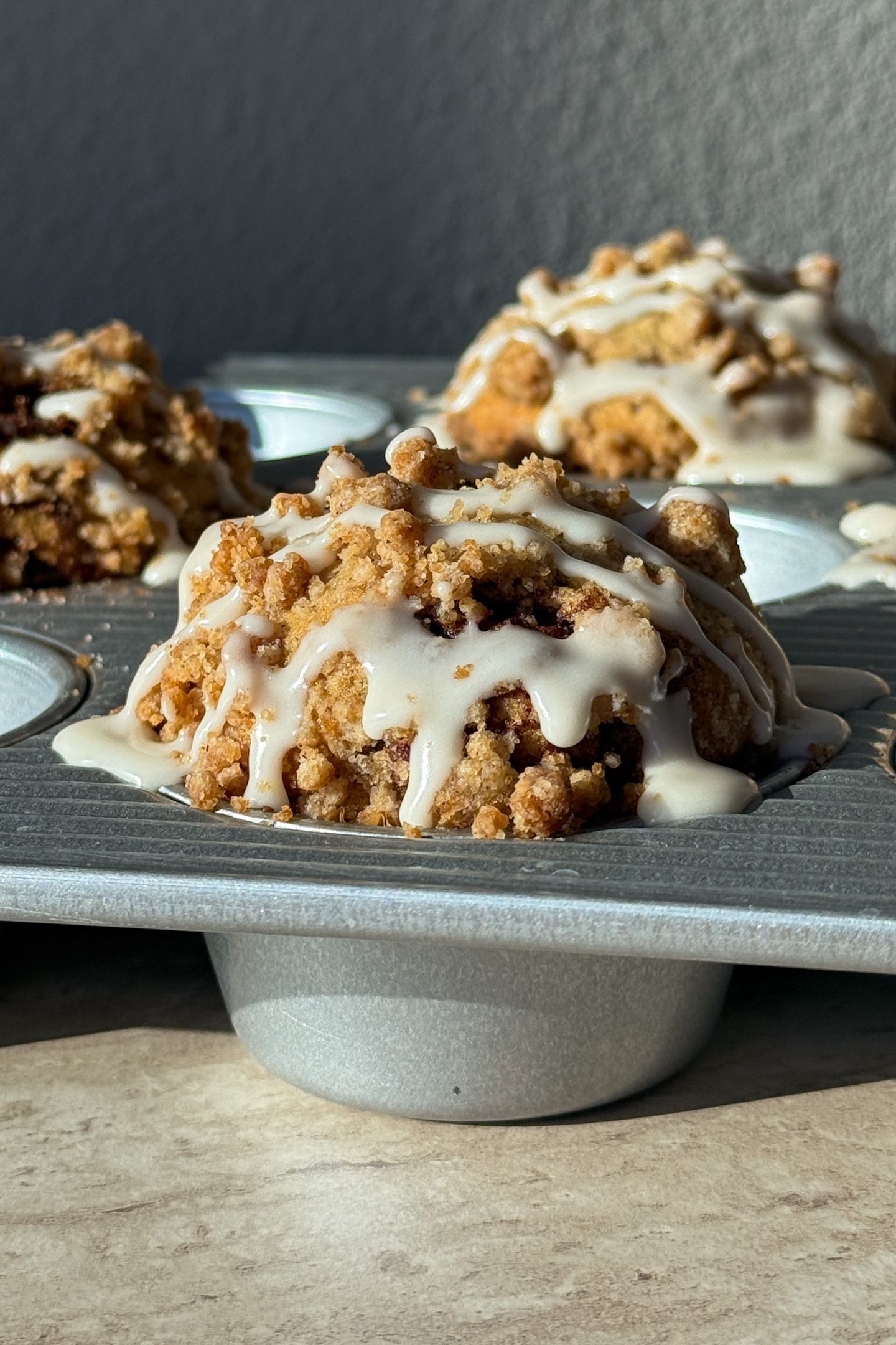 Baked muffins in the muffin tin topped with a vanilla glaze.