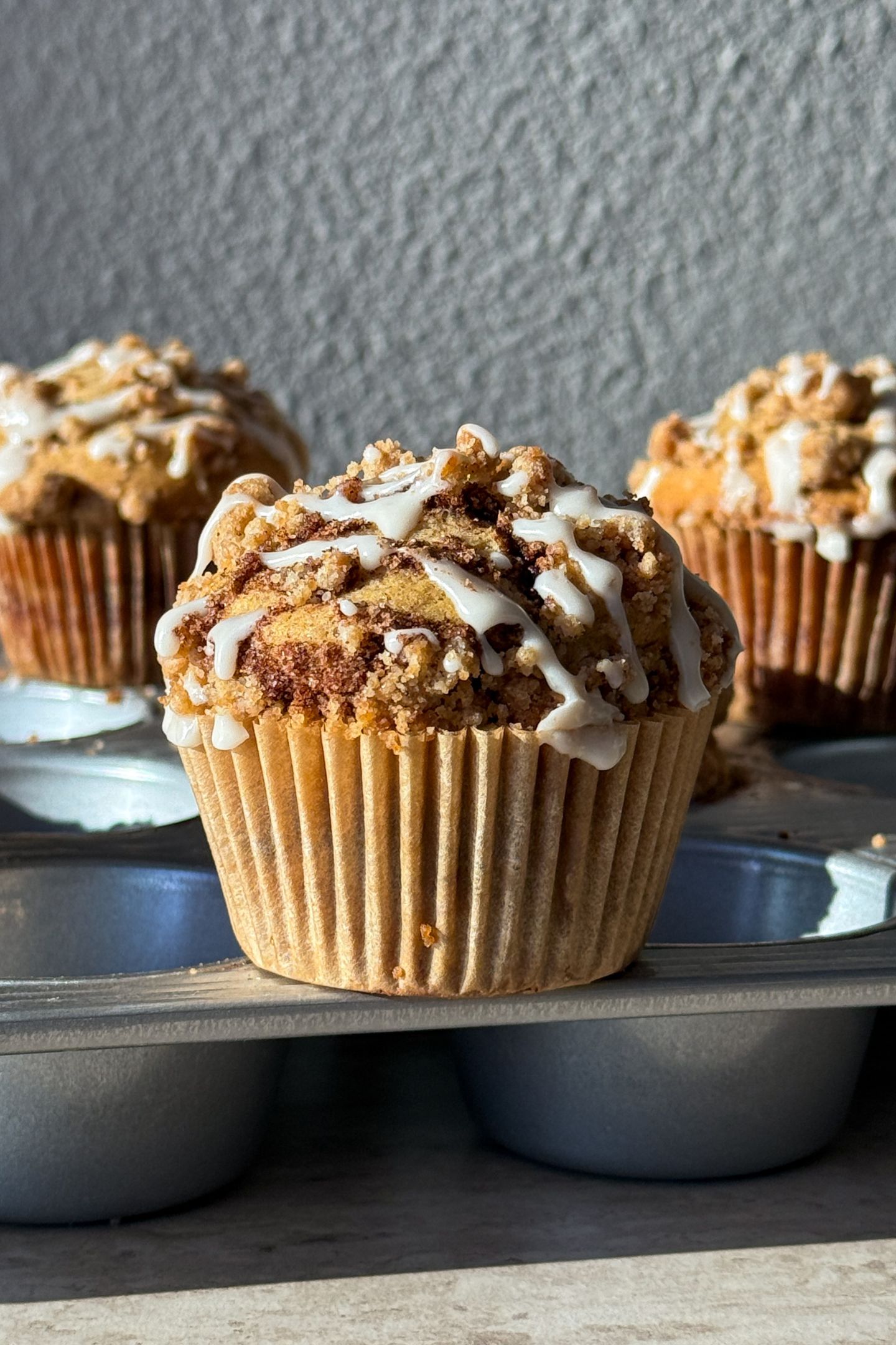 Cinnamon Streusel Muffins topped with a drizzle of vanilla glaze.