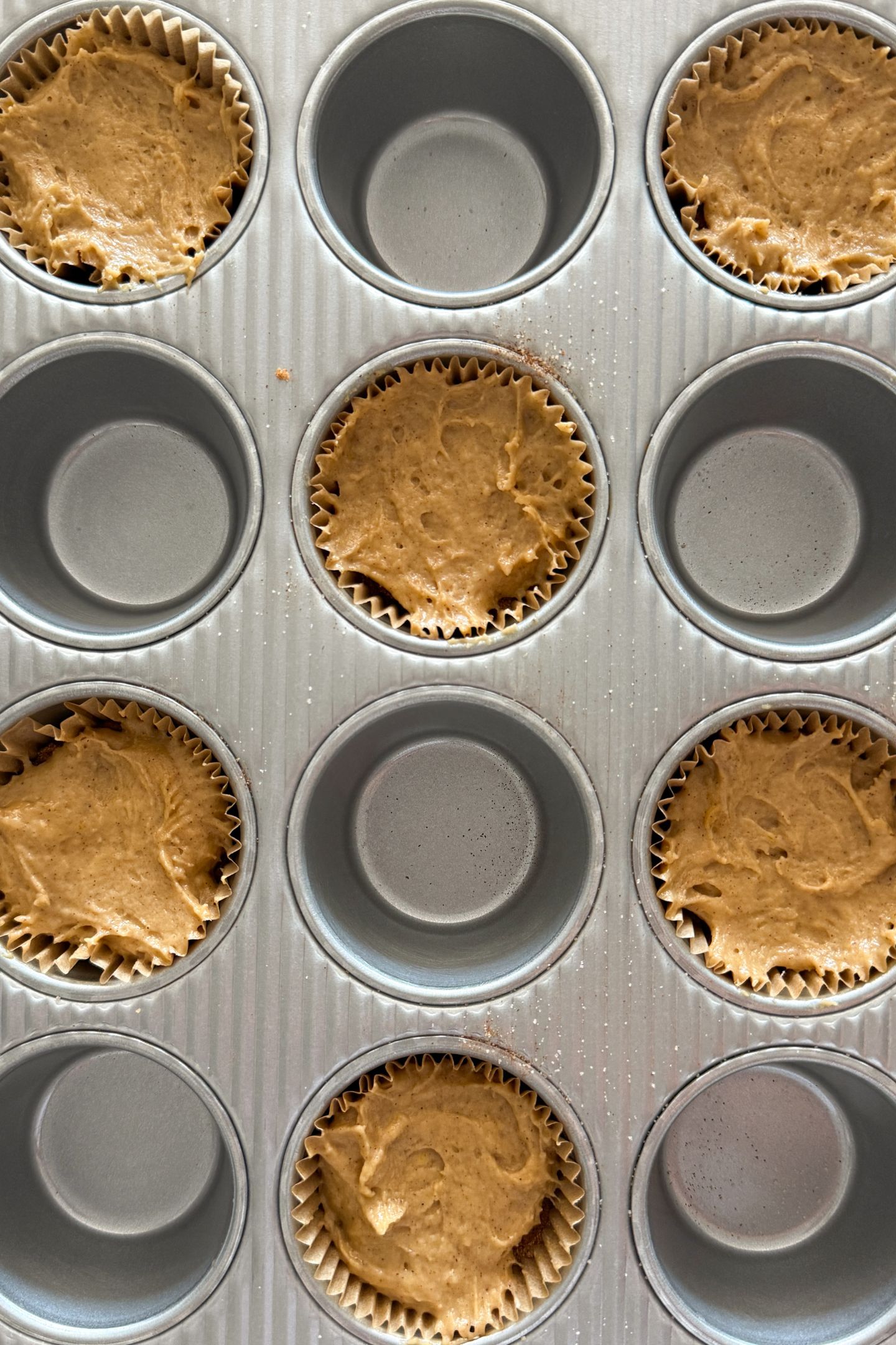 Assembling the cinnamon streusel muffins in the muffin tin.