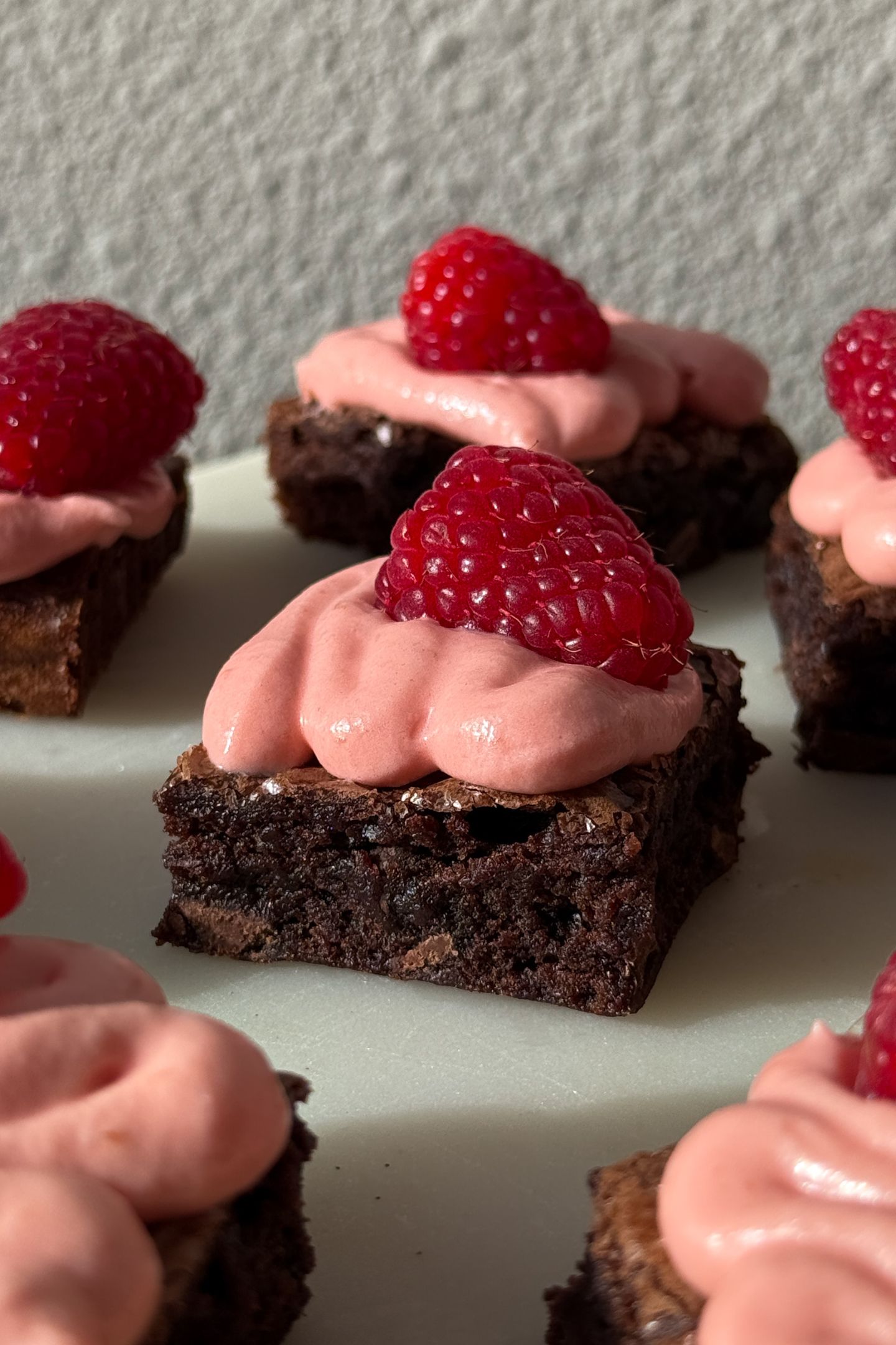 Side view of a brownie topped with raspberry cream cheese frosting.