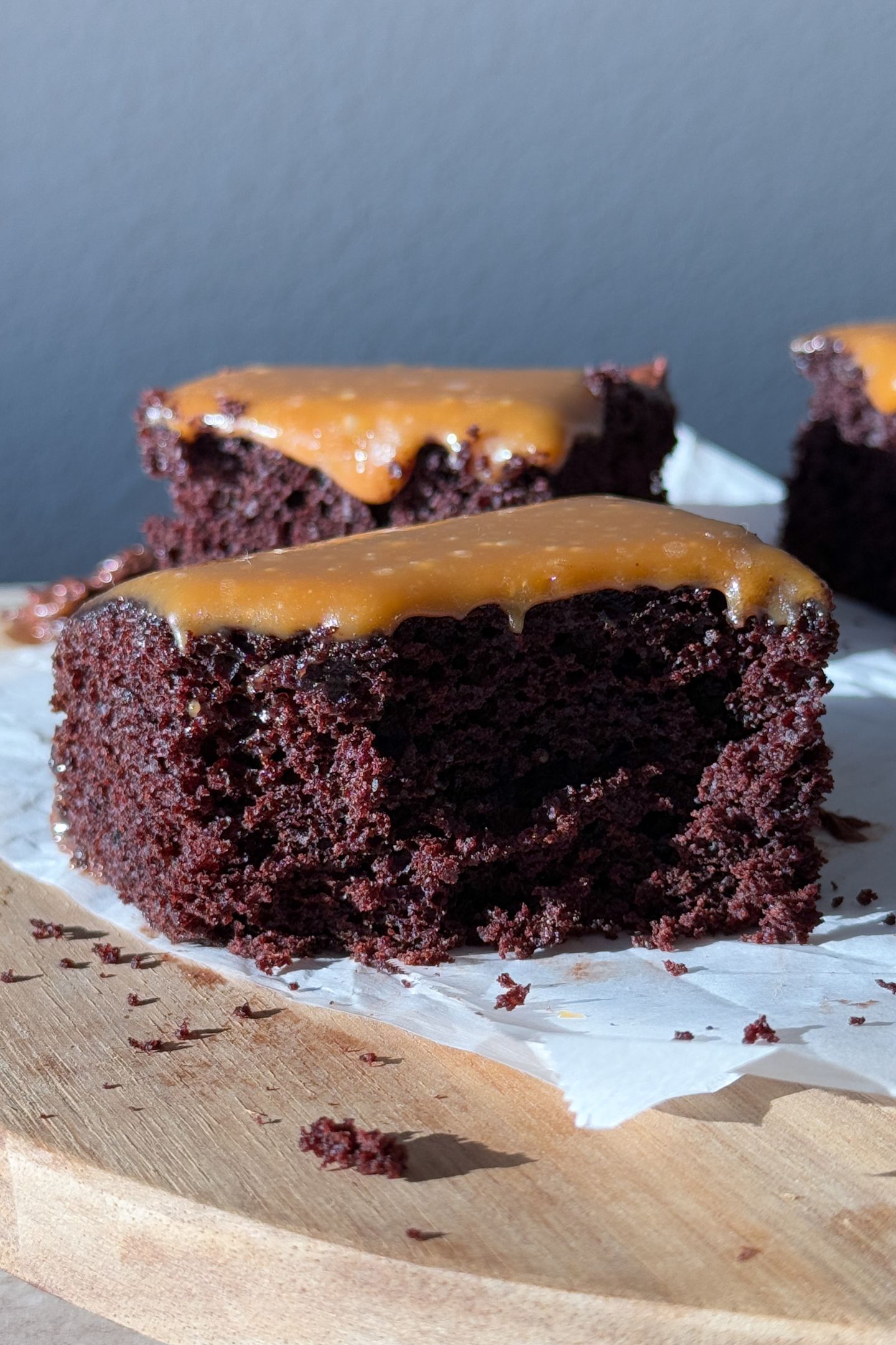 A slice of chocolate salted caramel cake with a piece taken out.