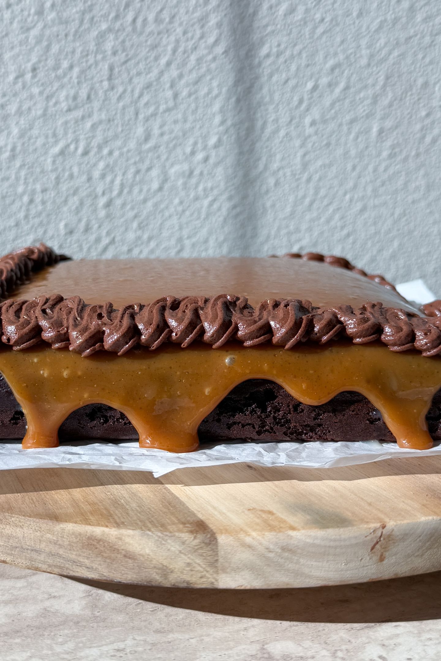 Piping the chocolate frosting on the edges of the cake.