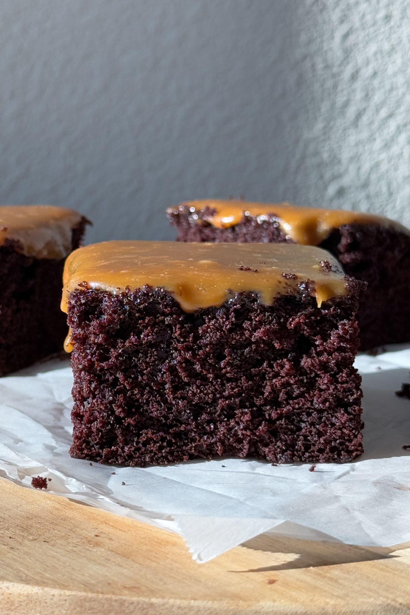 A slice of chocolate cake topped with homemade caramel sauce on a platter.