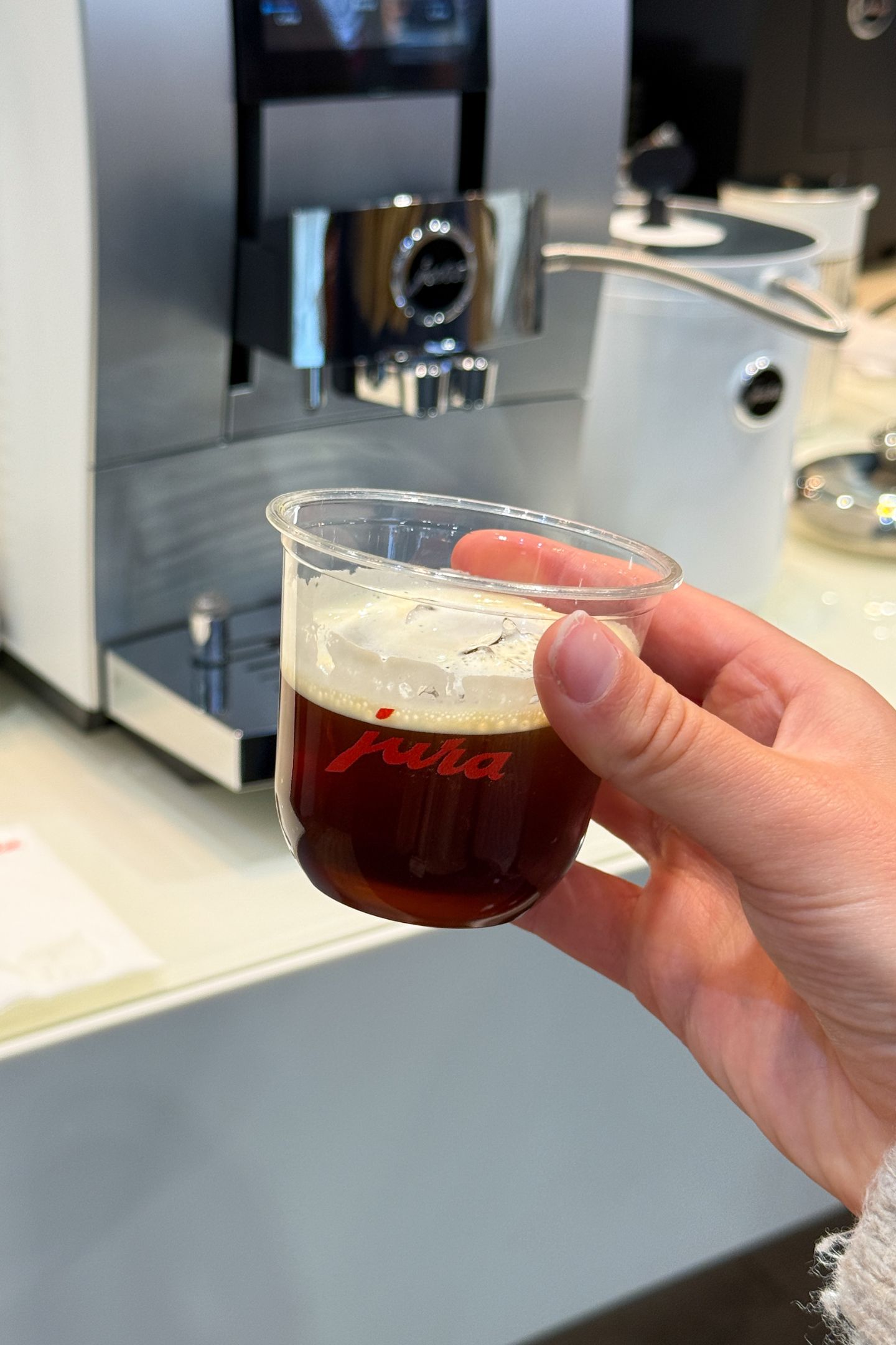 Holding a cup of cold brew coffee from the Jura machine.