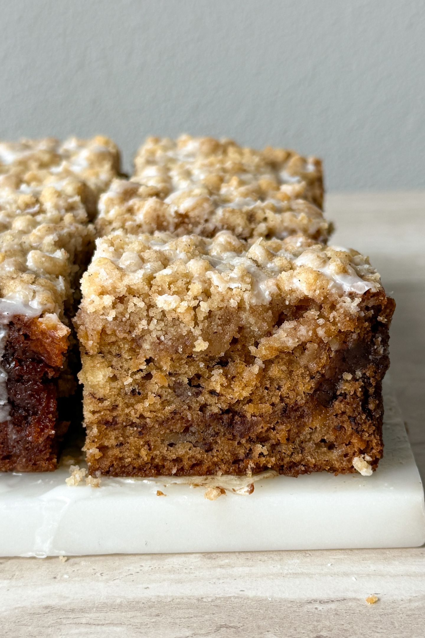 Side view of a slice of banana bread coffee cake topped with a vanilla glaze.