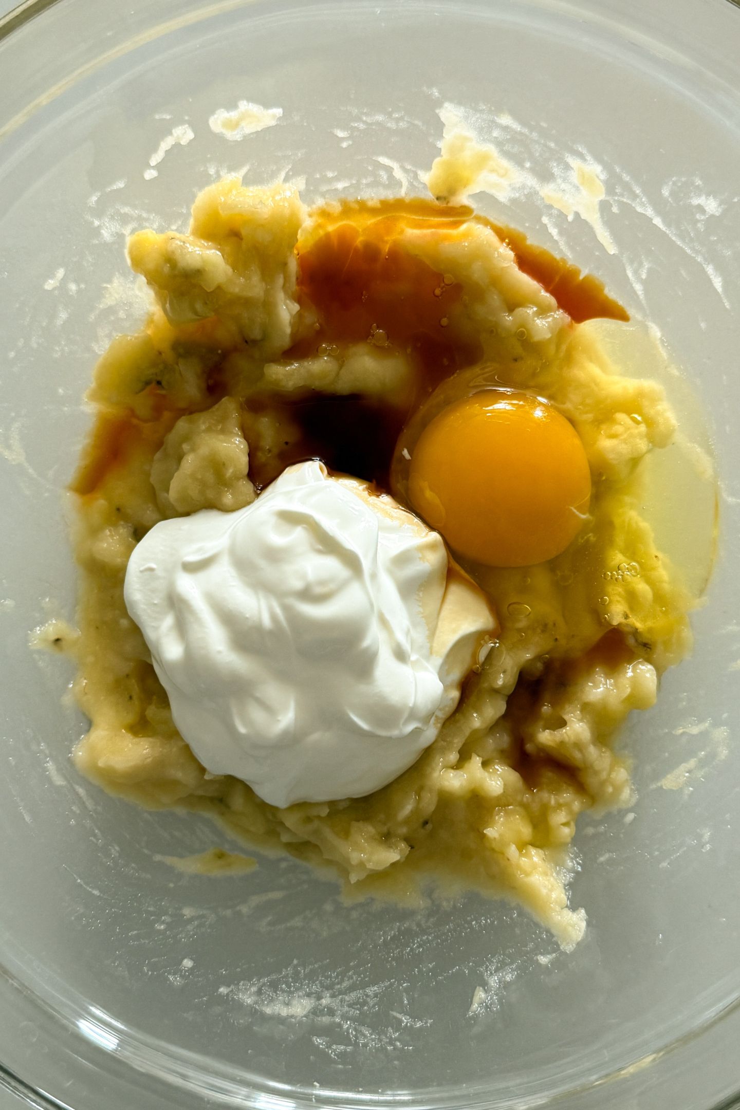 Mashed banana, egg, sour cream and vanilla in a bowl.