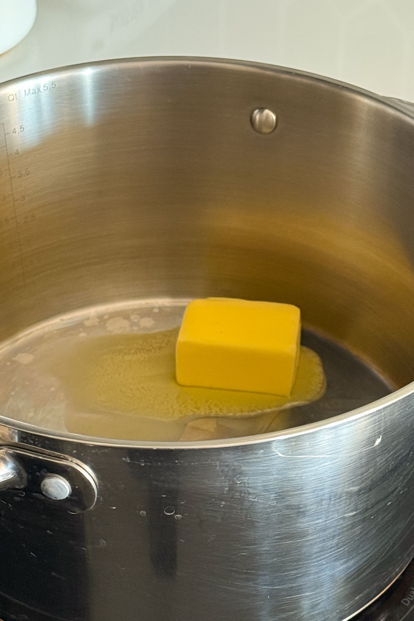 Adding salted butter to a large saucepan.