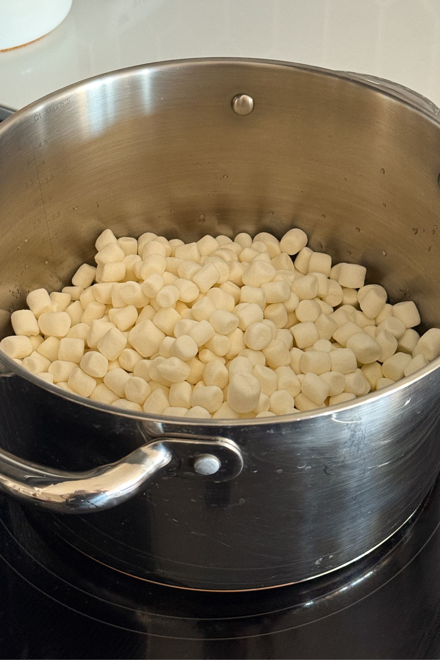 Adding mini marshmallows to the melted salted butter in a large saucepan.
