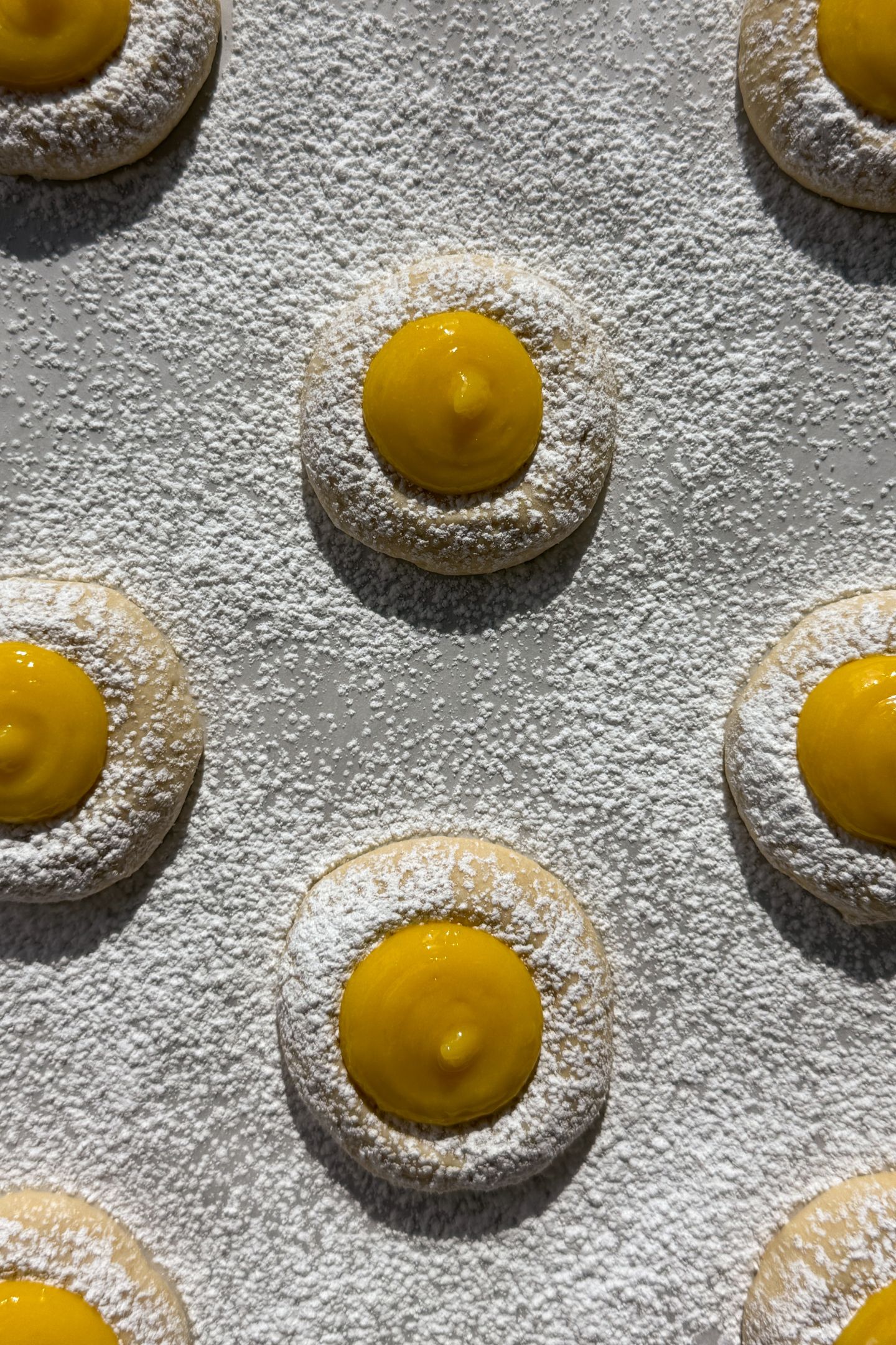 Cookies on parchment paper filled with lemon curd in the center.
