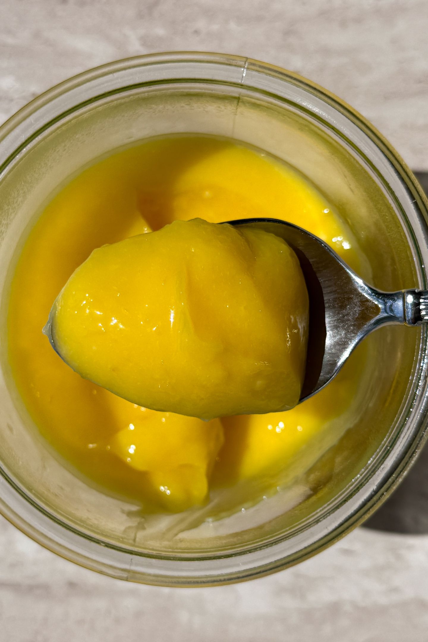 A spoonful of lemon curd over a mason jar.