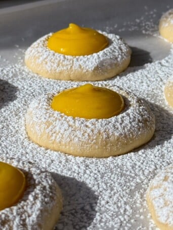 Side view of lemon curd cookies on a baking sheet lined with parchment paper.