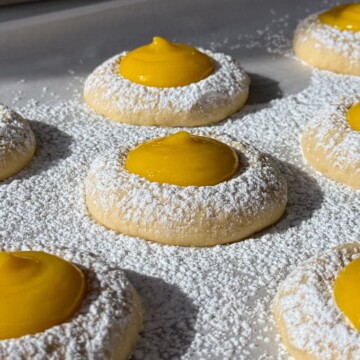 Side view of lemon curd cookies on a baking sheet lined with parchment paper.