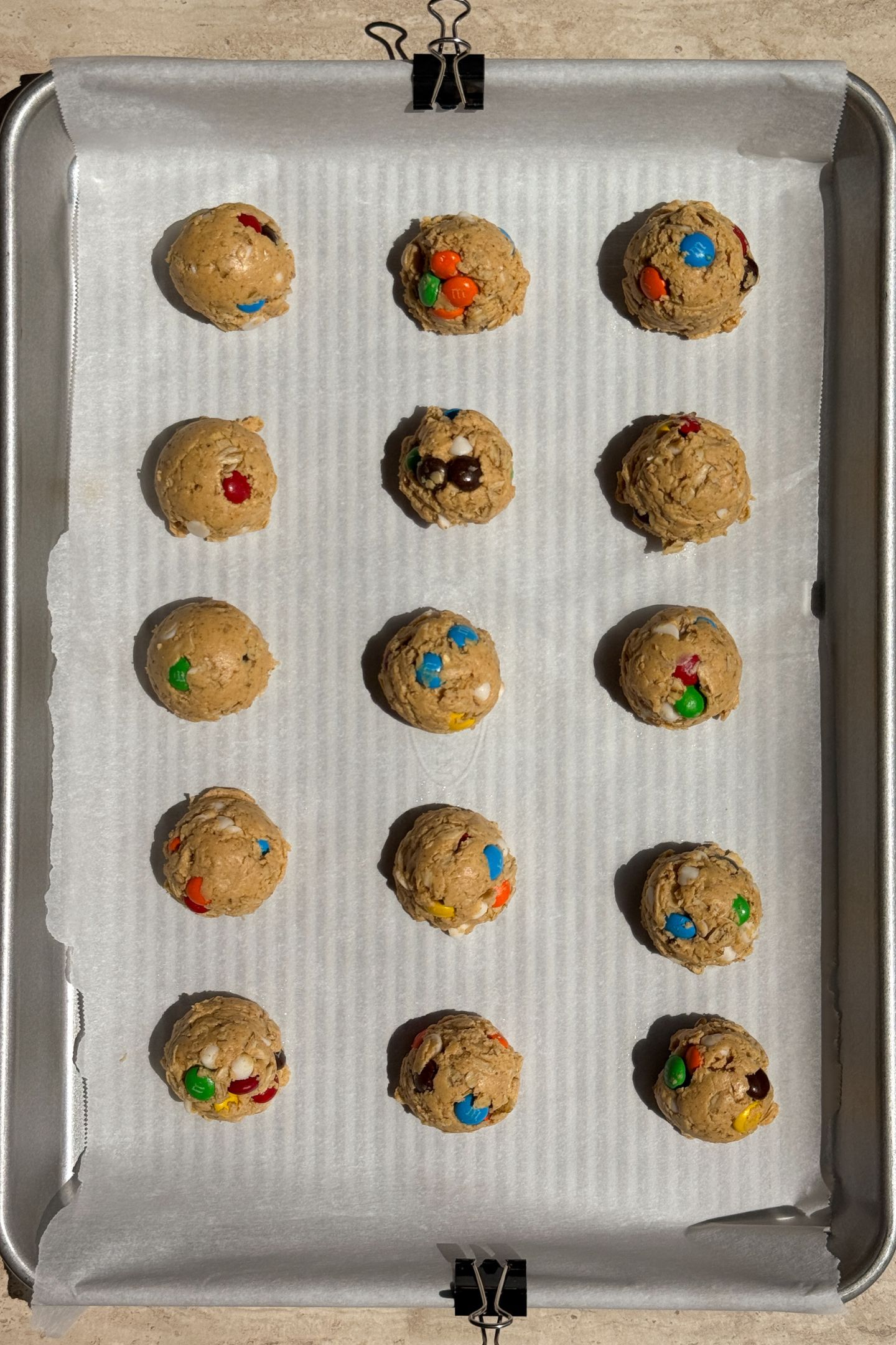 Monster cookie protein balls on a baking sheet lined with parchment paper.