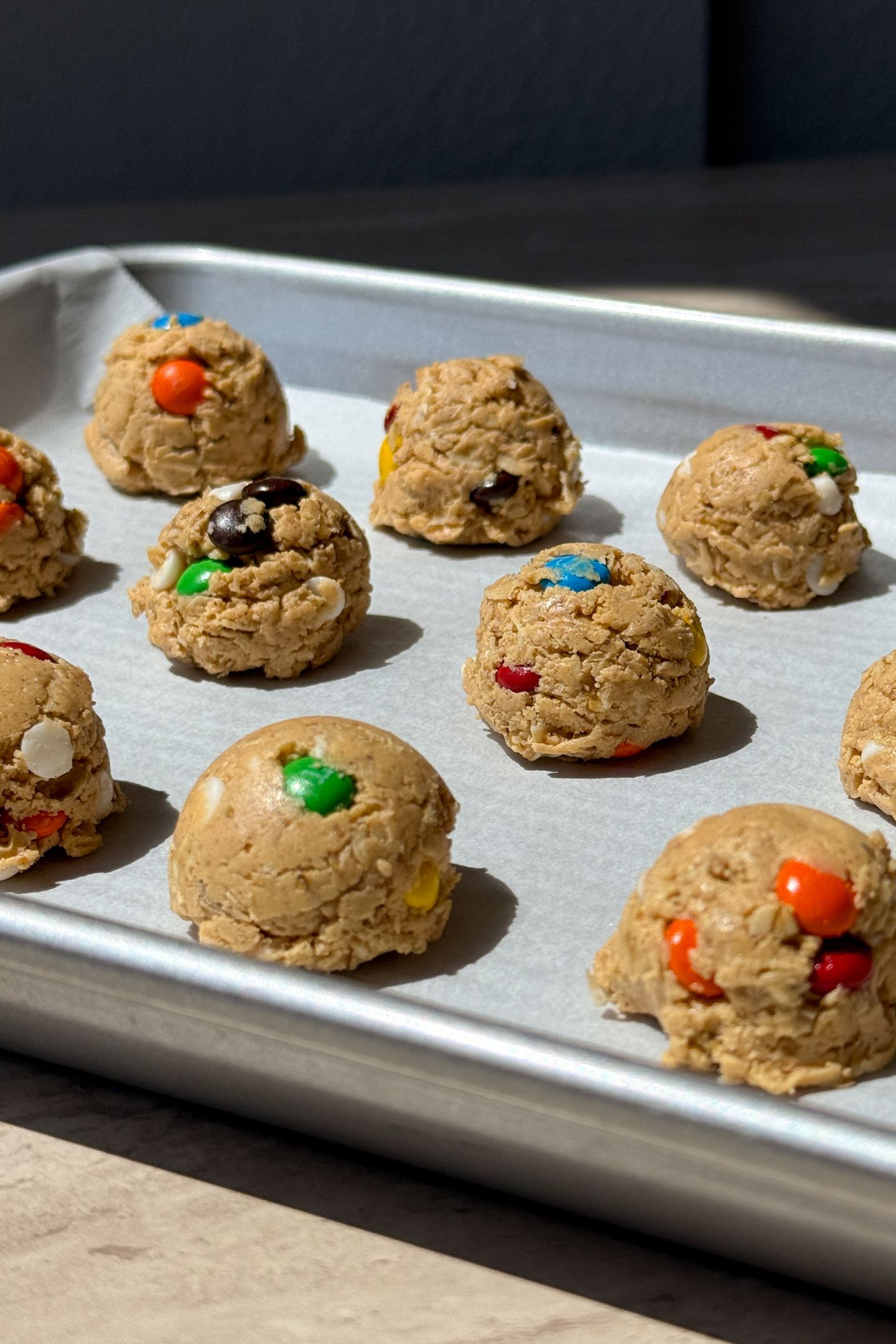 Monster cookie protein balls on a baking sheet lined with parchment paper.