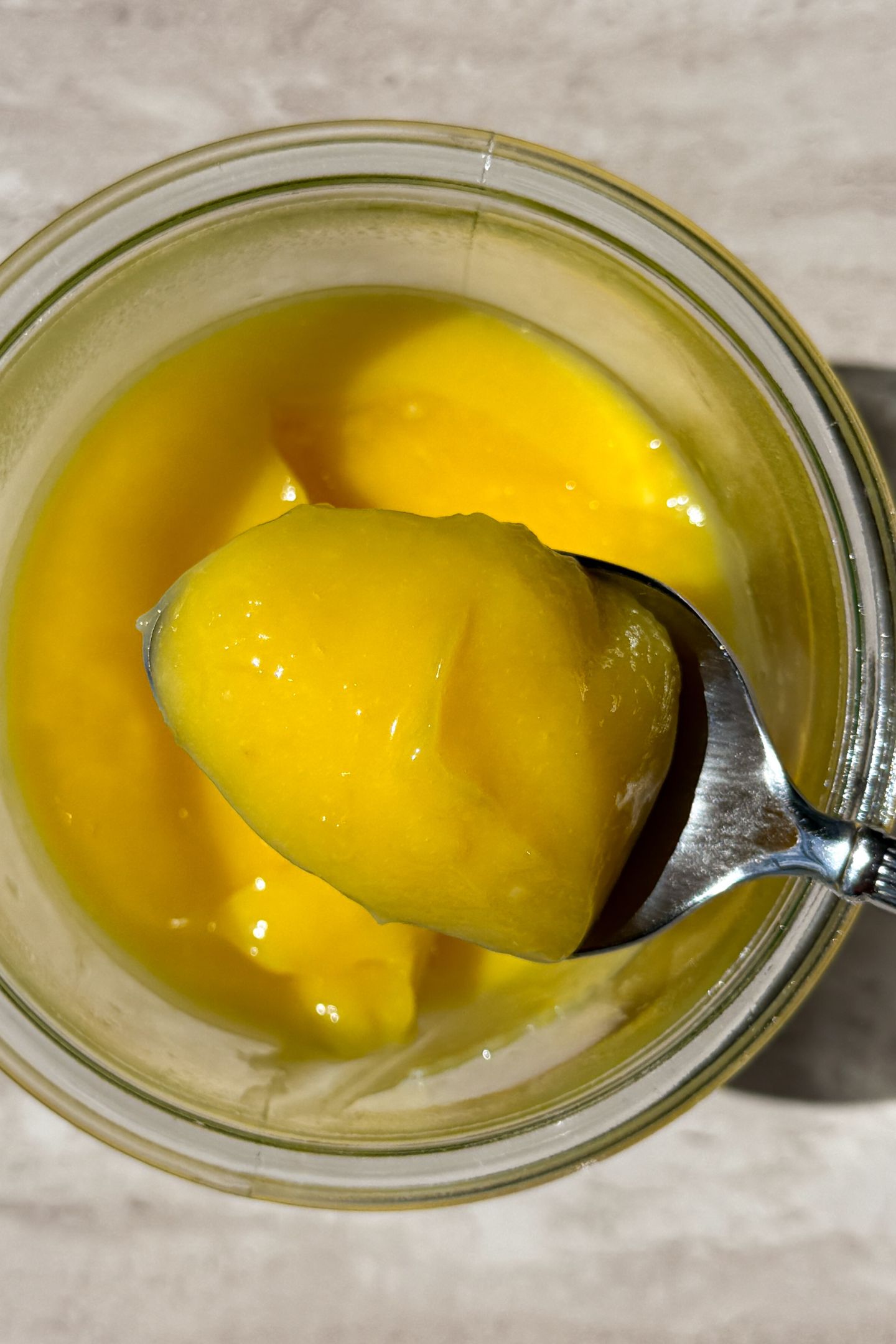 Spooning the lemon curd out of a mason jar.