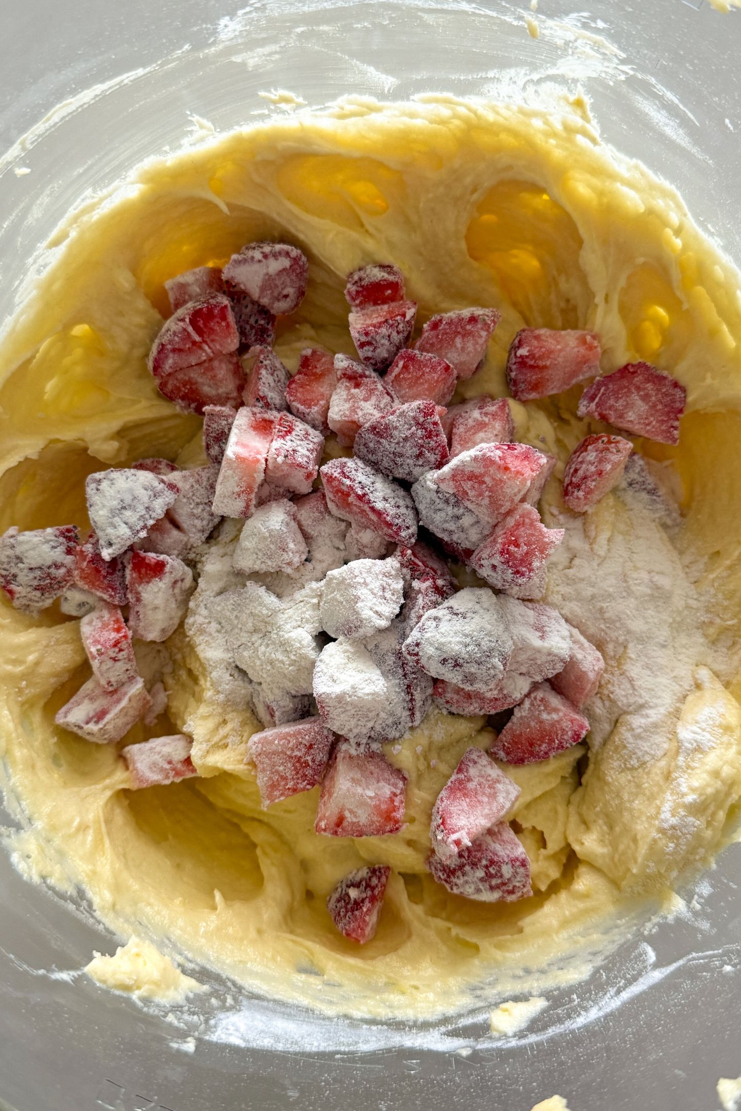 Adding the coated fresh strawberries to the lemon pound cake batter in the mixing bowl.