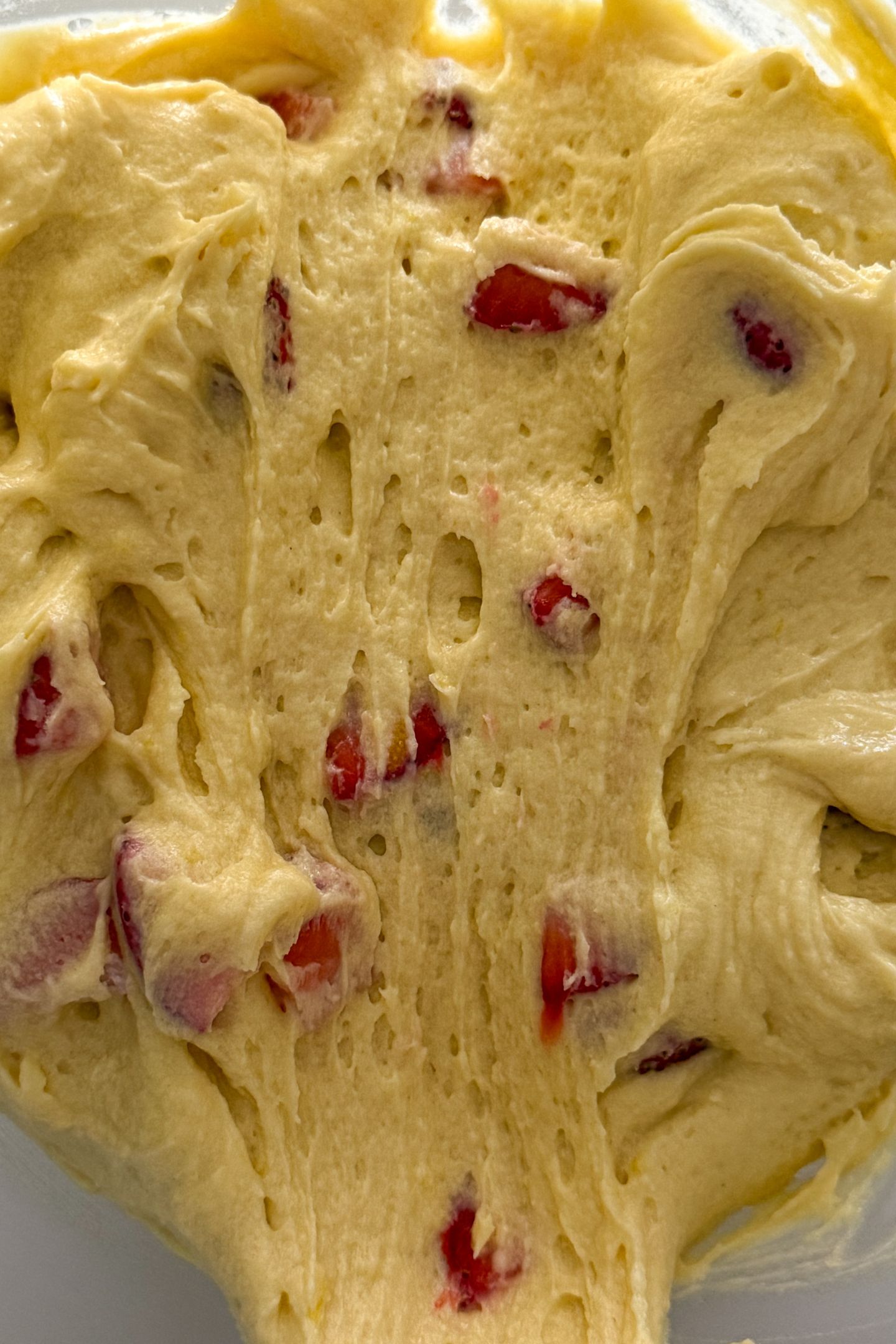 The coated fresh strawberries are mixed into the lemon pound cake batter in the mixing bowl.