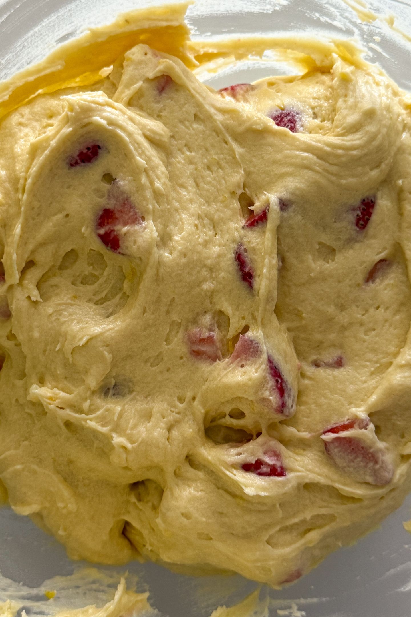 The coated fresh strawberries are mixed into the lemon pound cake batter in the mixing bowl.