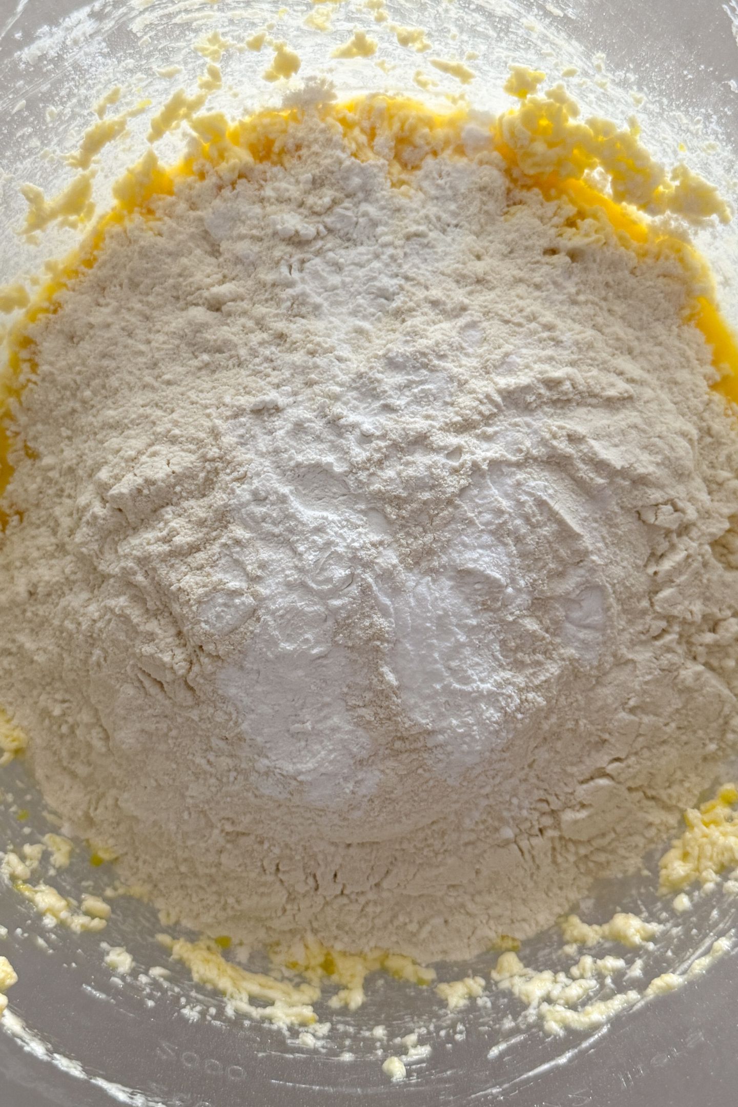 Adding flour, baking powder and baking soda to the wet ingredients in a mixing bowl.