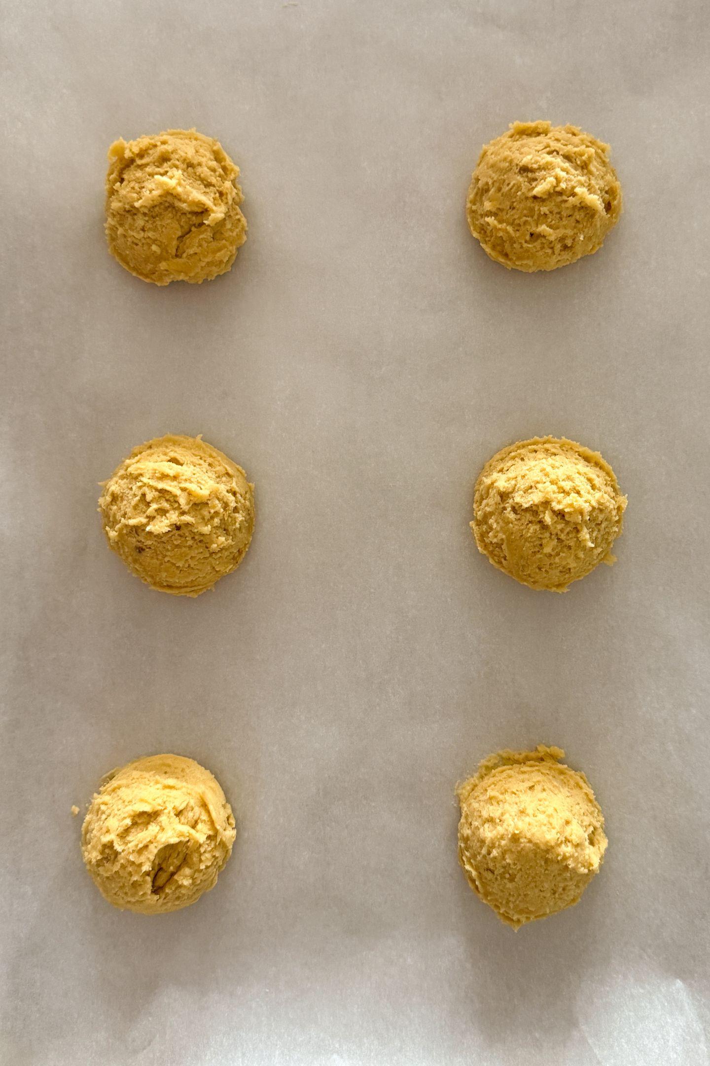 Cookie dough portioned out on parchment paper.