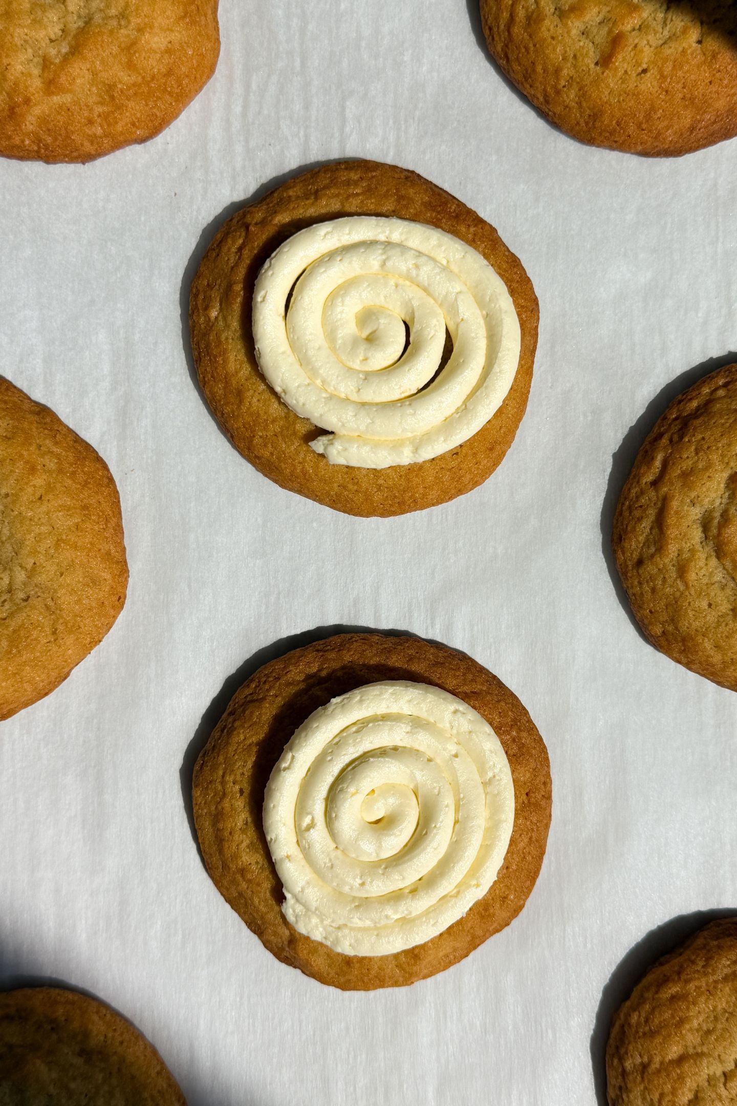 Banana pudding cookies on parchment paper topped with a banana buttercream frosting.