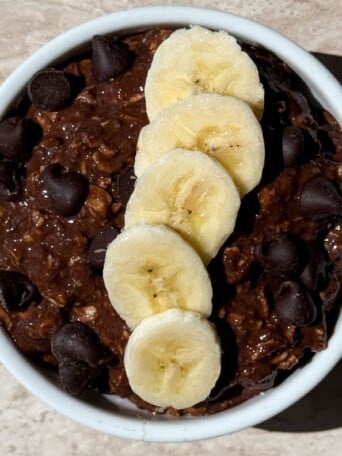 Chocolate Banana Overnight Oats prepared in a bowl with toppings added on.