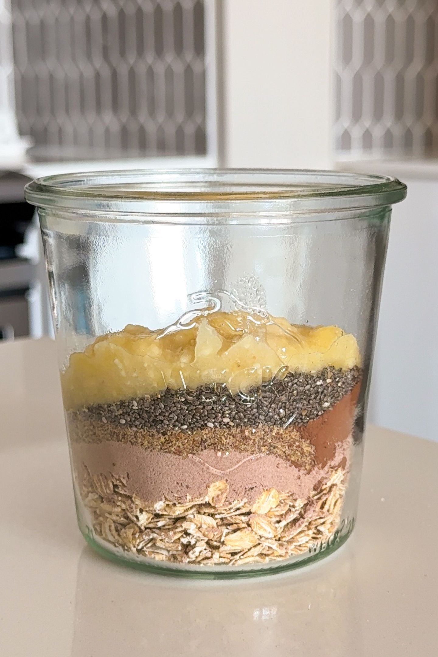 Adding mashed banana to the dry ingredients in a mason jar.