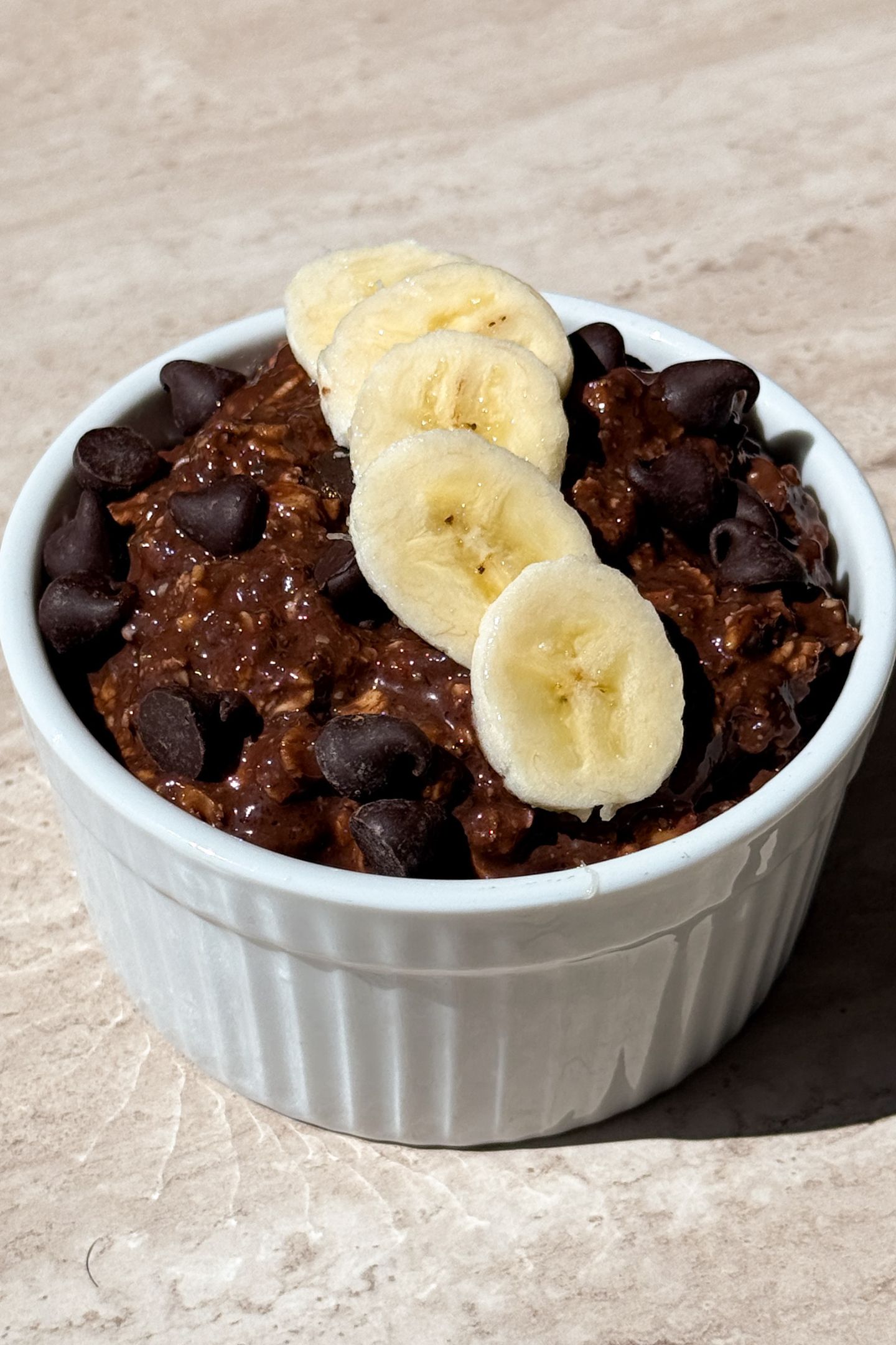 Chocolate banana overnight oats topped with chocolate chips and slices of fresh banana.