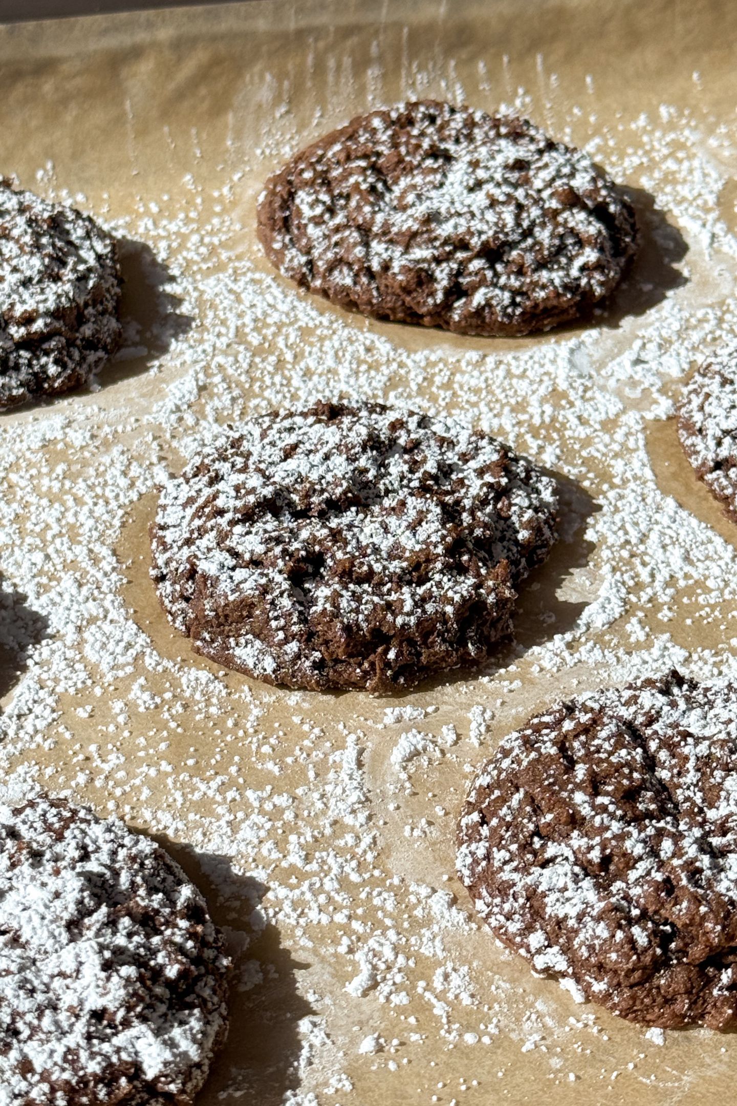 Chocolate Cake Mix Cookies on a baking sheet lined with parchment paper that have been topped with powdered sugar.