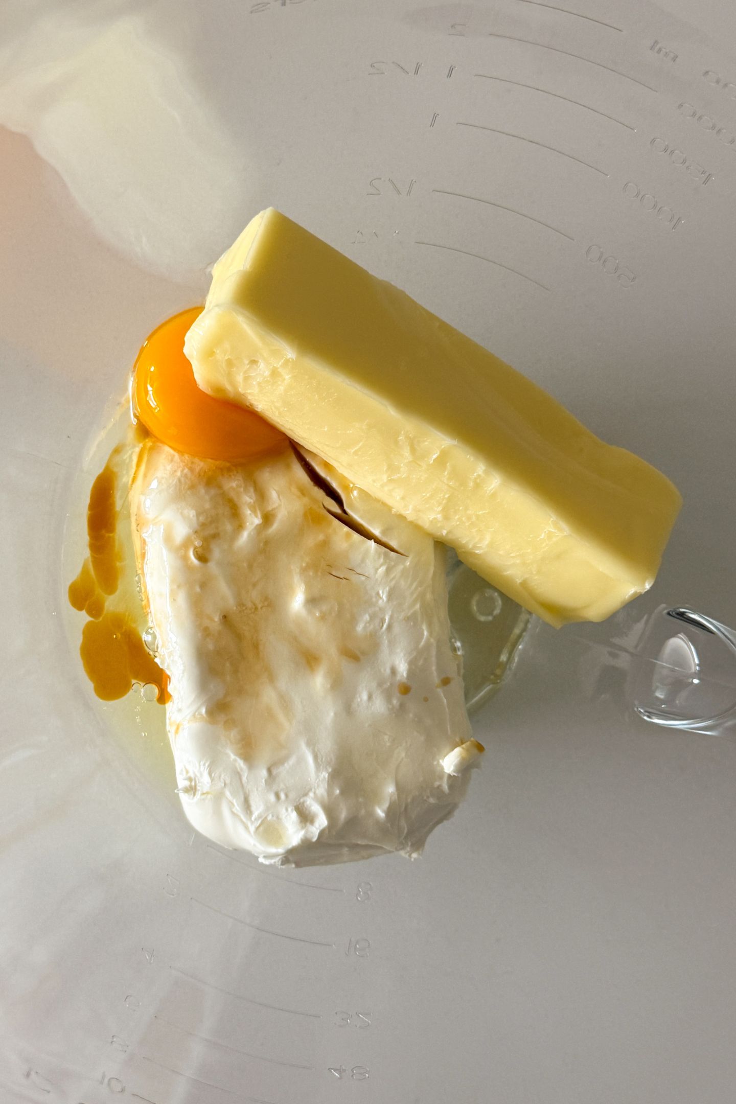 Butter, cream cheese, vanilla extract and an egg in a mixing bowl.