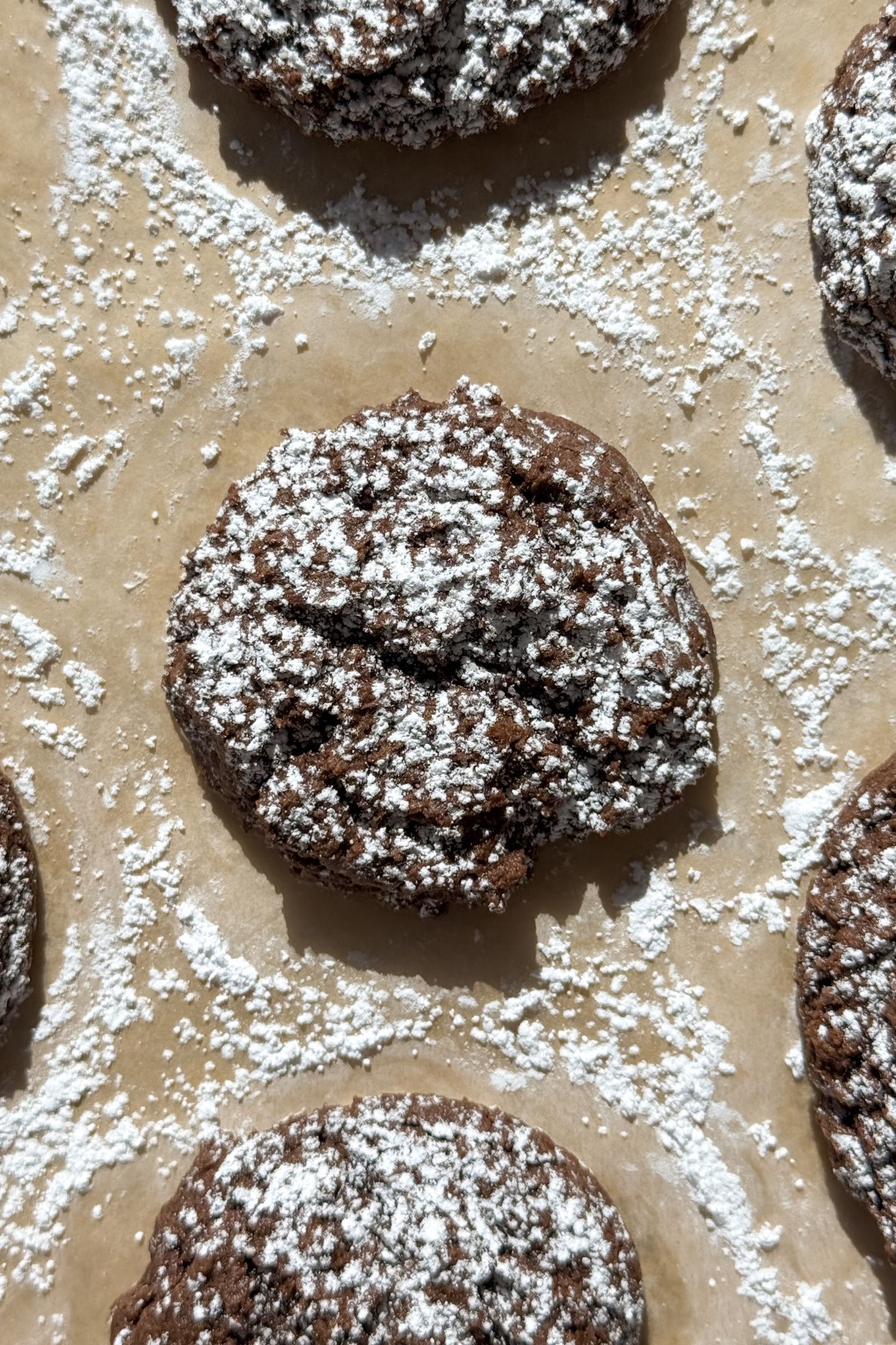 Close up shot of a chocolate cake mix cookie made with cream cheese that is topped with powdered sugar.