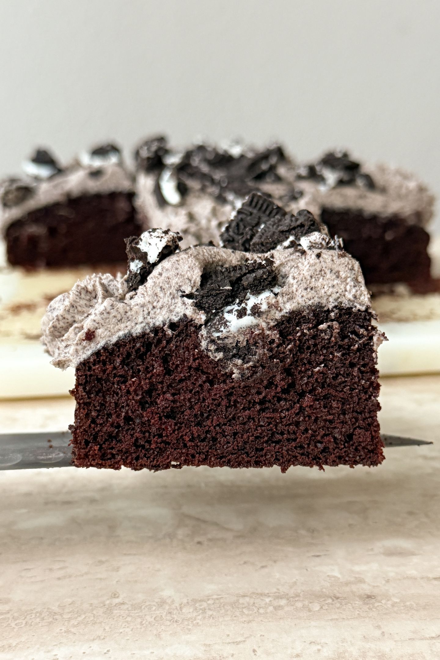 A slice of chocolate cookies and cream cake on a knife.