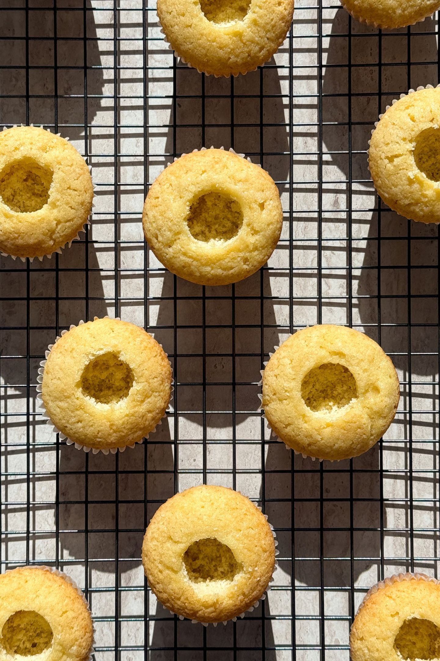 Baked cupcakes on a cooling rack with the core taken out.