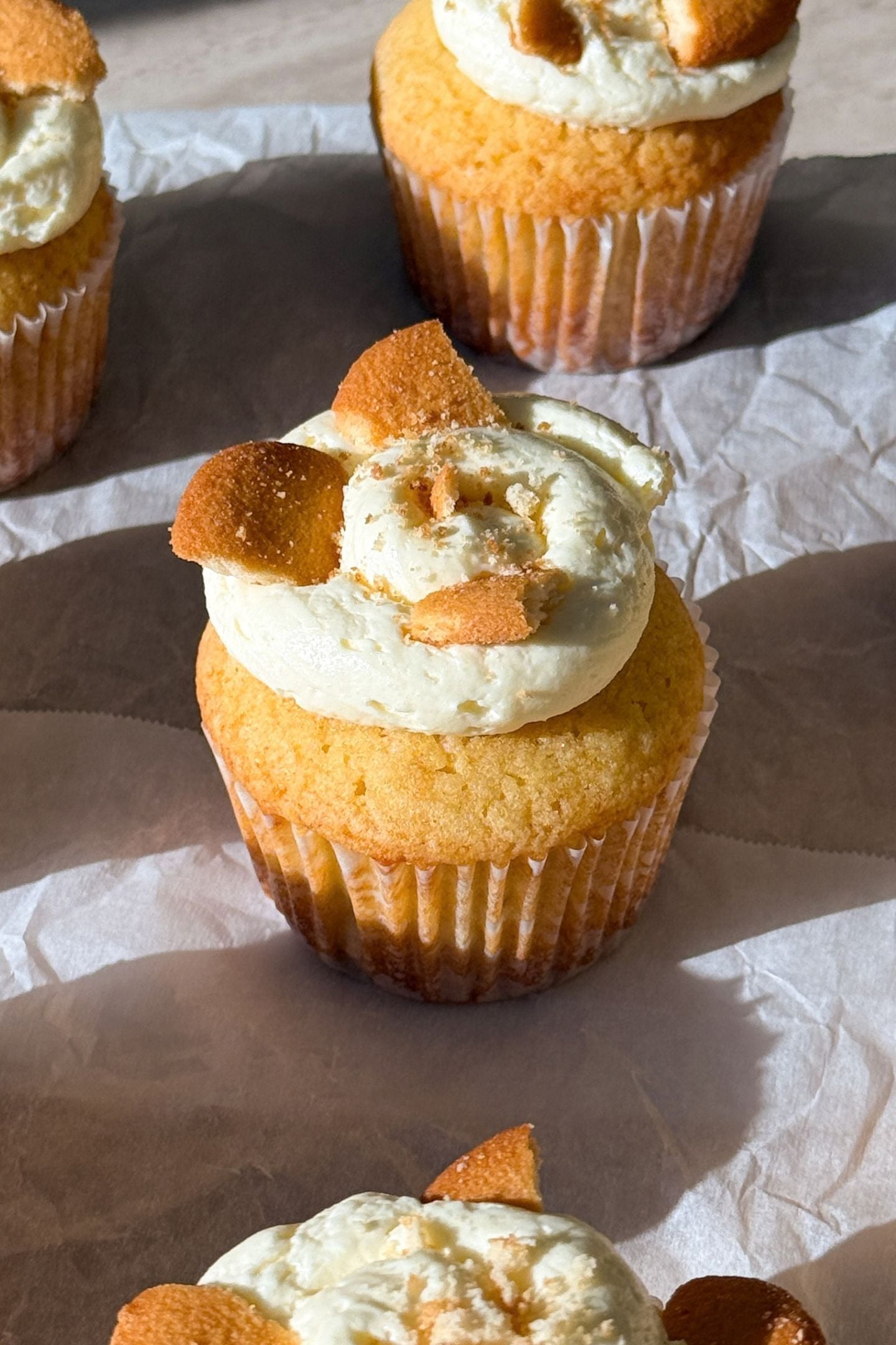 Banana pudding cupcakes on a platter and topped with banana pudding buttercream and crushed vanilla wafer cookies.