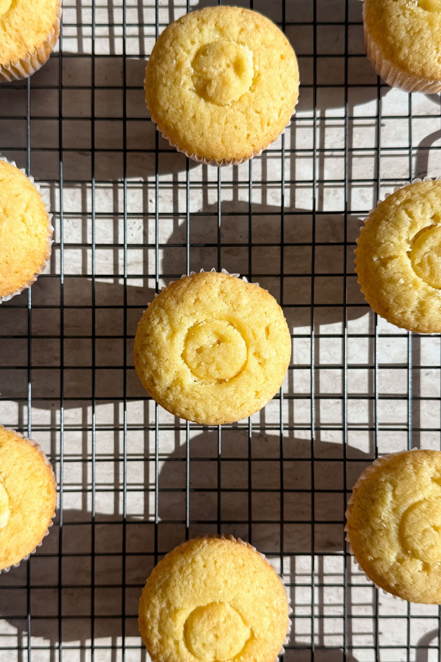 Baked cupcakes on a cooling rack, with the core taken out and filled with banana pudding.
