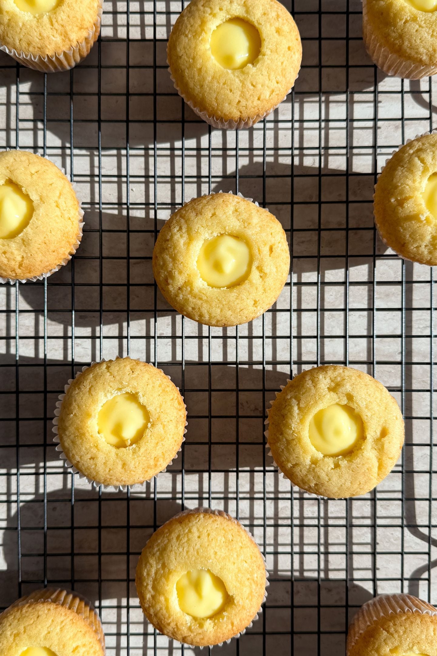 Baked cupcakes on a cooling rack, with the core taken out and filled with banana pudding.