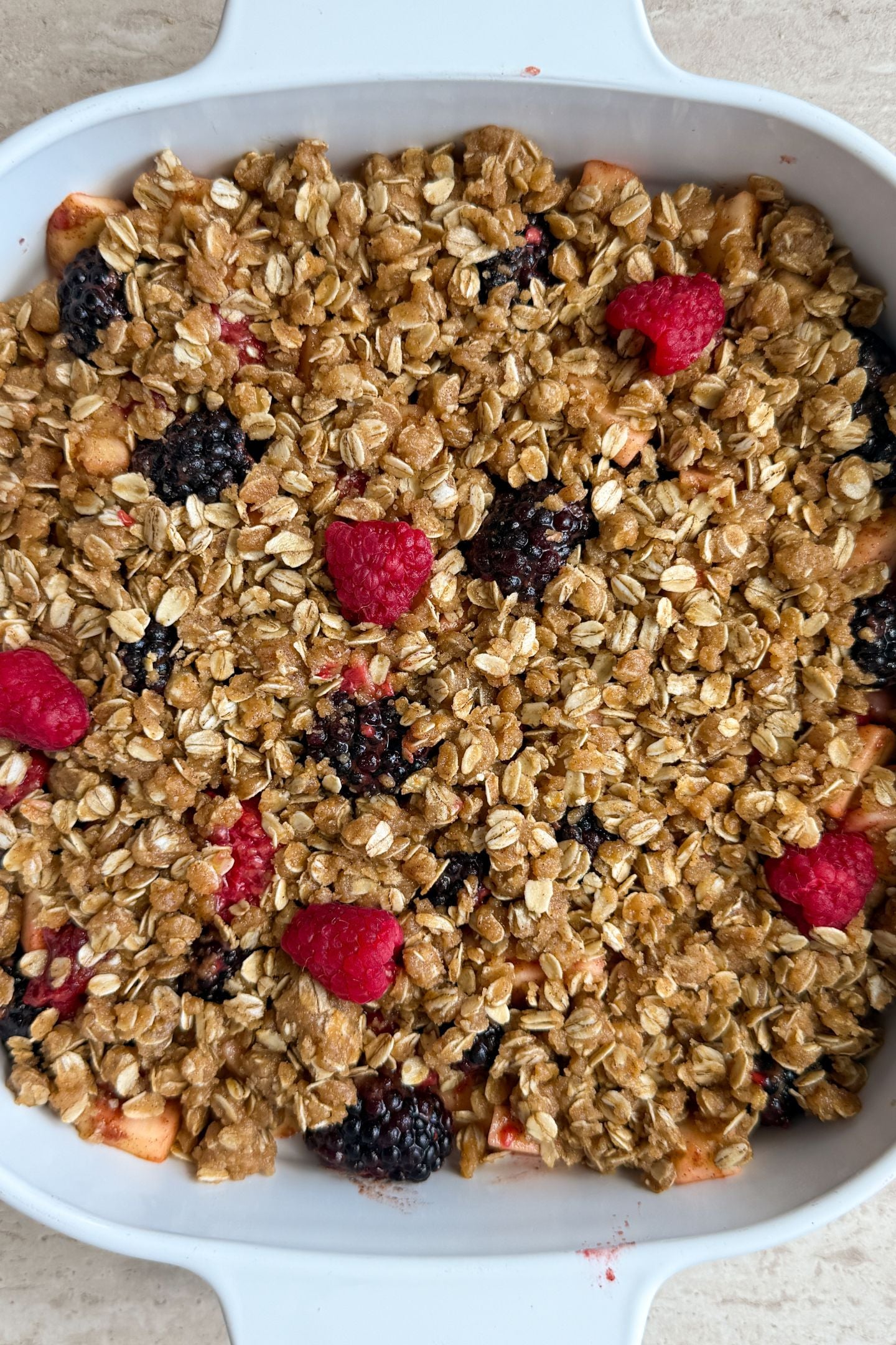 Adding the crisp topping on top of the mixed berries and apples.