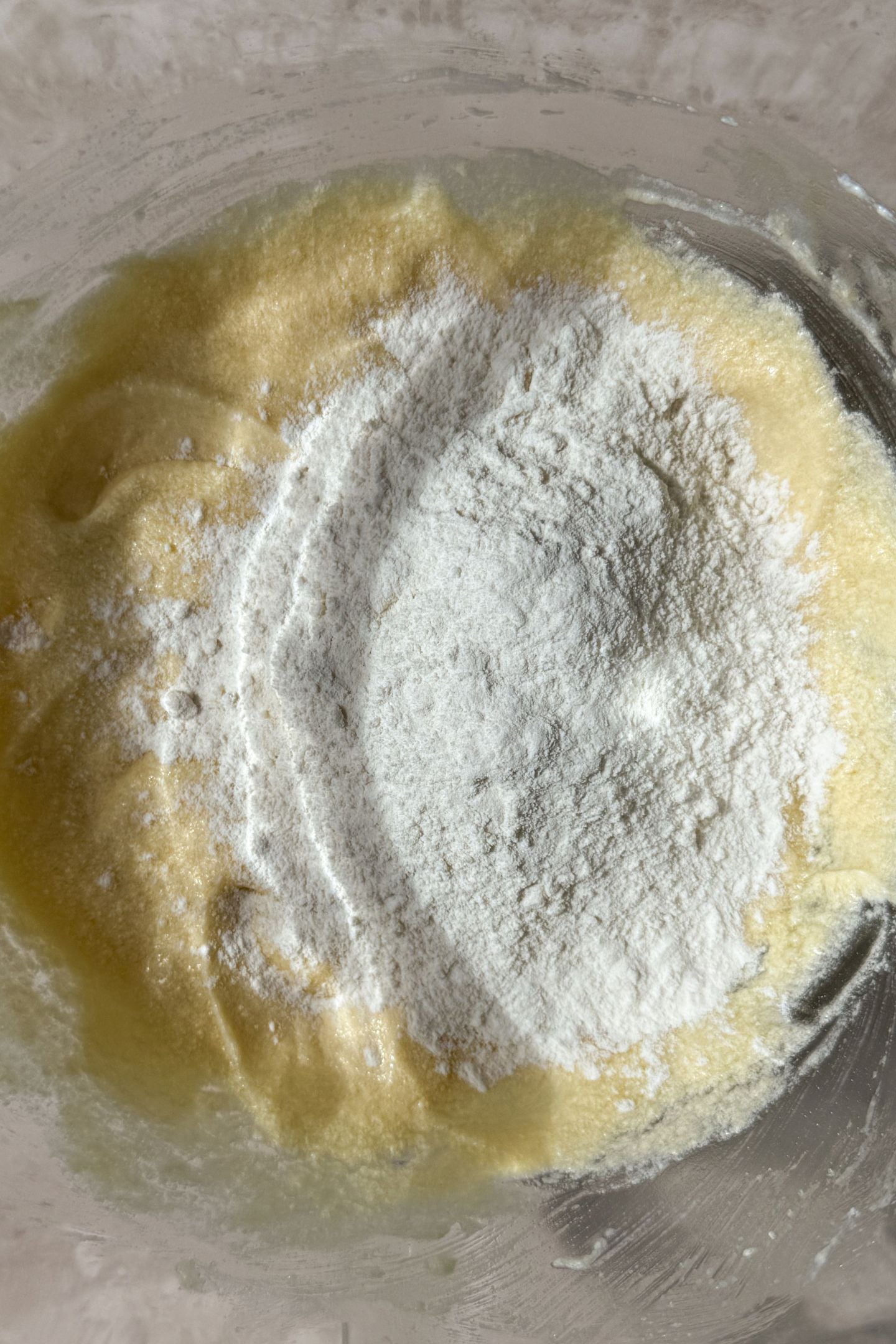 Adding half of the flour to the wet ingredients in the mixing bowl.