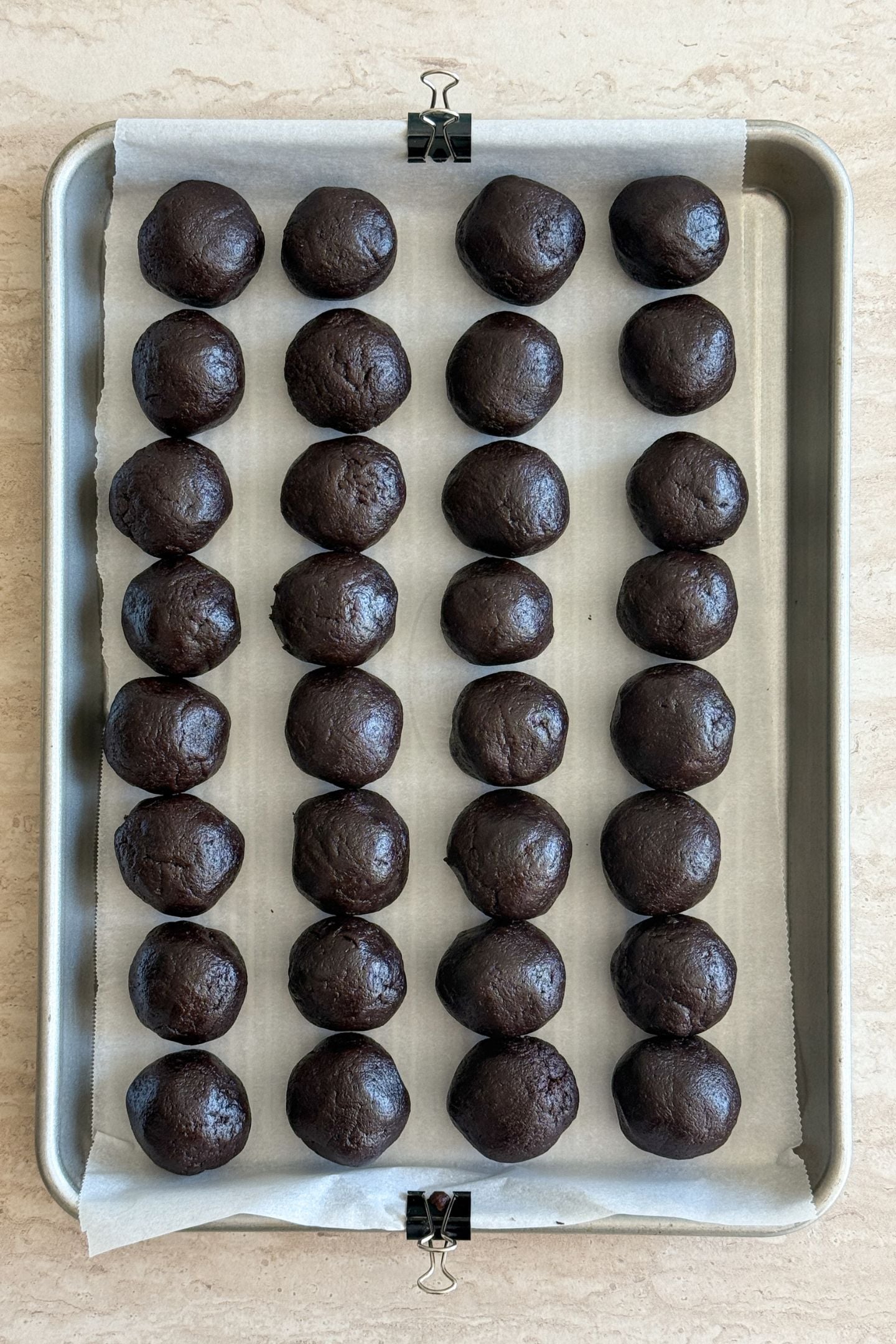 Cake pops portioned and rolled into balls on a baking sheet lined with parchment paper.